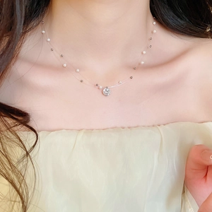 Detail of double-layer necklace with pearl and zircon pendant on a transparent line