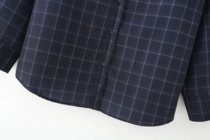 Dettaglio della camicia in popeline a quadri blu navy che mostra bottoni e l'orlo