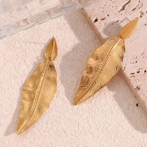 Macro shot of 18K gold plated feather earrings on a stone and glass texture