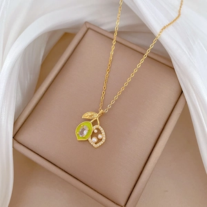 Detail of gold necklace with green lemon pendant and pearls on silk fabric