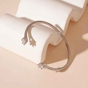 Detail view of silver C-shaped open bangle with two round cubic zirconia stones