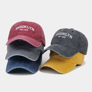 Detail of washed cotton baseball caps in burgundy, navy, and yellow with Brooklyn embroidery