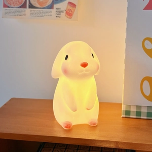 Detail of cute rabbit night light with soft warm glow on a wooden shelf for cozy decor