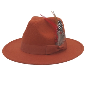 Detailansicht eines rostorangen Fedora-Hutes mit eleganter Schleife und bunten Zierfedern