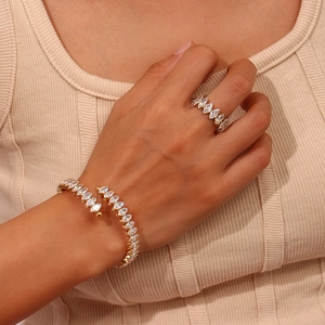 Dettaglio di set bracciale e anello dorati regolabili con zirconi marquise su modella