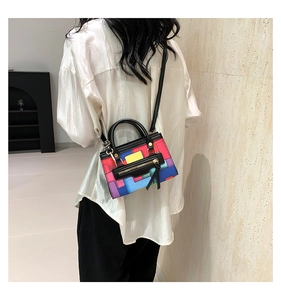 Detail of colorful geometric patchwork handbag with gold hardware and black handles
