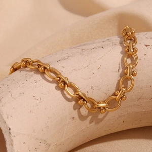 Gros plan détaillé des maillons ovales plaqués or 18 carats avec boules métalliques sur bracelet