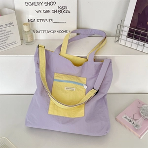 Detail of canvas tote bag showing contrast yellow zipper pocket and purple fabric texture