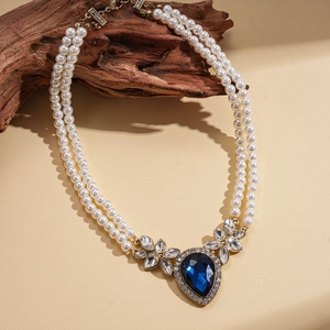 Vue détaillée du collier de perles double rang avec un grand pendentif goutte bleu