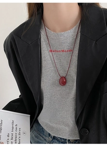 Close-up of a dark red oval resin pendant on a matching wax cord necklace for women