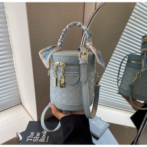 Close-up of light blue woven bucket bag with patterned silk scarf wrapped on handle