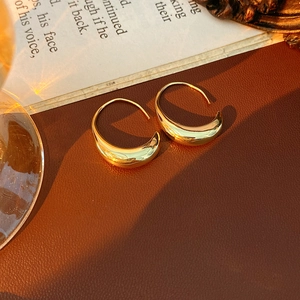 Artistic detail of 14k gold plated drop earrings on a vintage leather background