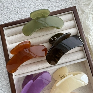 Detailed view of five colorful jelly hair claws in a wooden box with velvet lining