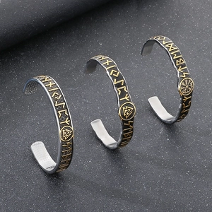 Detail of silver Viking bangles with gold runes and Valknut knot on dark background