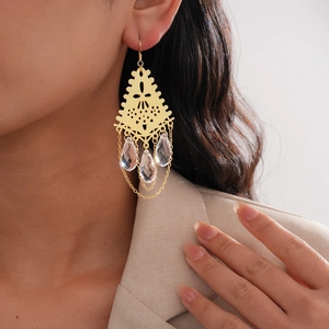 Détail de boucles d'oreilles bohèmes dorées avec pompons métalliques et perles de verre