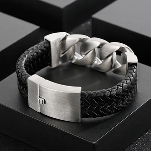Detail of woven black leather and brushed steel Cuban chain bracelet on a black display