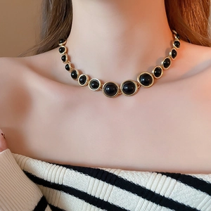 Close-up of model wearing resin round pendant necklace with gold metal inlay