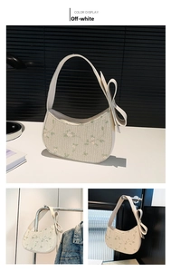 Detail view of cream crescent bag with green floral embroidery and large side leather bow