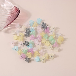 Mini matte flower hair claws in macaron colors scattered on a beige background