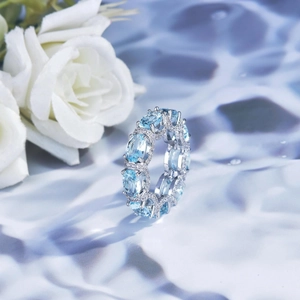 Macro shot of silver eternity ring featuring oval blue gemstones and pavé accents