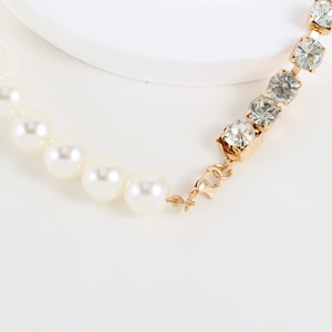 Close-up of asymmetric pearl and rhinestone necklace with golden metal clasp details