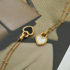 Detail of 18K gold plated necklace featuring black and white shell heart pendants