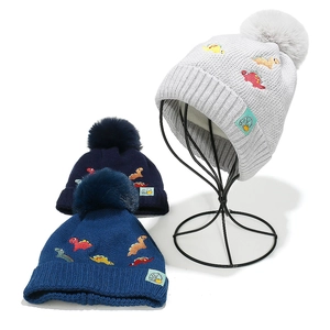 Winter knit baby earflap hat with dinosaur embroidery and fluffy pom pom details