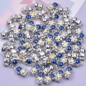 Silver astronaut pendants with blue helmets and yellow stars on a purple background