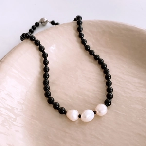Detailed macro of black glass beads and white baroque pearls on a ceramic plate