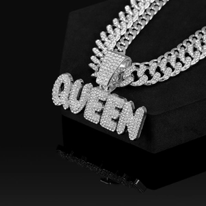Macro del ciondolo QUEEN con strass scintillanti su una catena cubana di lusso