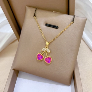 Macro detail of gold-tone necklace featuring cherry-shaped pink heart stones and diamonds