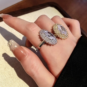 Detail of gold and silver rings with large oval cubic zirconia in double-layer halo setting