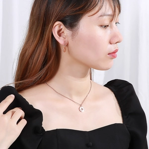 Gros plan d'une parure de bijoux boussole en or rose avec collier et boucles d'oreilles