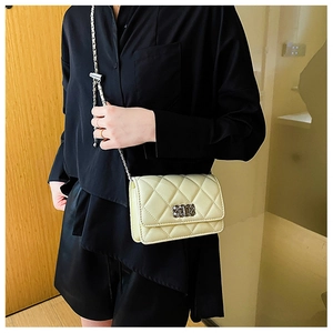 Detailed view of yellow quilted crossbody bag featuring silver chain strap and metal lock
