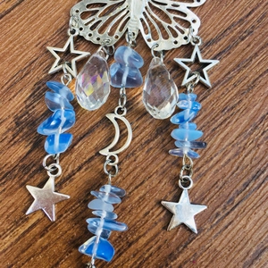 Detail of silver suncatcher with butterfly and moon pendants plus blue stones on wood