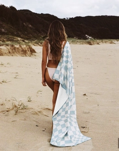 Model showing a long light blue and white checkered quick-dry beach towel by the sea