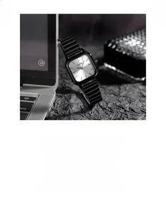 Detail showing GEDI square watch with silver dial and black steel strap on workspace