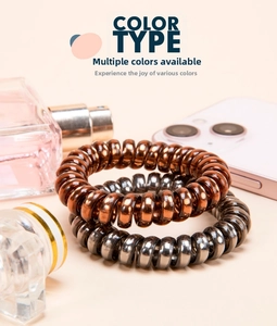 Close-up of metallic spiral telephone wire hair ties in bronze and gunmetal grey finishes