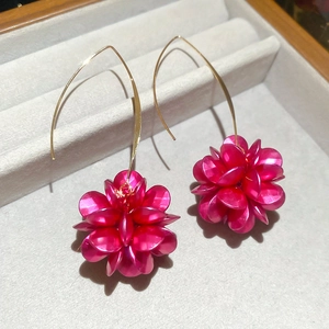 Vista macro di orecchini a fiore fucsia con ganci dorati in scatola di velluto