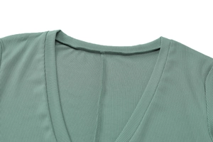 Close-up of green ribbed knit fabric showing the V-neckline detail and fine stitching
