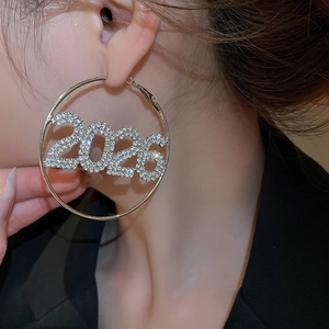 Primo piano di orecchini a cerchio con strass e numero 2026 indossati da modella