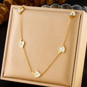 Detail of gold necklace with white mother-of-pearl leaf charms in a jewelry gift box