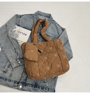 Detail of brown quilted tote bag with floral embroidery and detachable small pouch