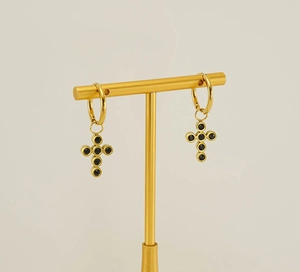 Detail of gold stainless steel hoop earrings with black zircon cross charm on T-stand