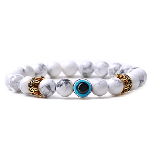 Detailed view of white marble turquoise beads with gold crowns and blue evil eye charm