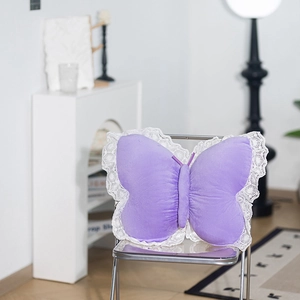 Detail of purple butterfly plush pillow featuring white lace trim on a transparent chair