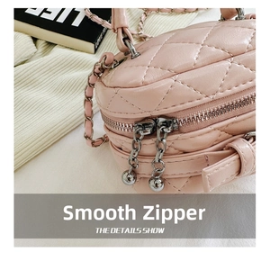 Detail of pink quilted handbag with silver dual zippers and metallic ball charms