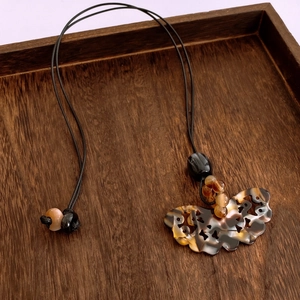 Détail du pendentif papillon évidé en résine ambrée avec cordon noir tressé vintage