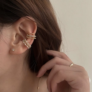 Detail of layered gold ear cuffs with pearls and crystals on a female ear