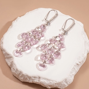 Détail de boucles d'oreilles pompons cœur en cristal rose avec accents de zircon